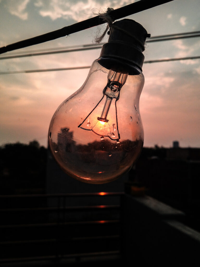 Vertical shot of a light bulb against the sunset sky