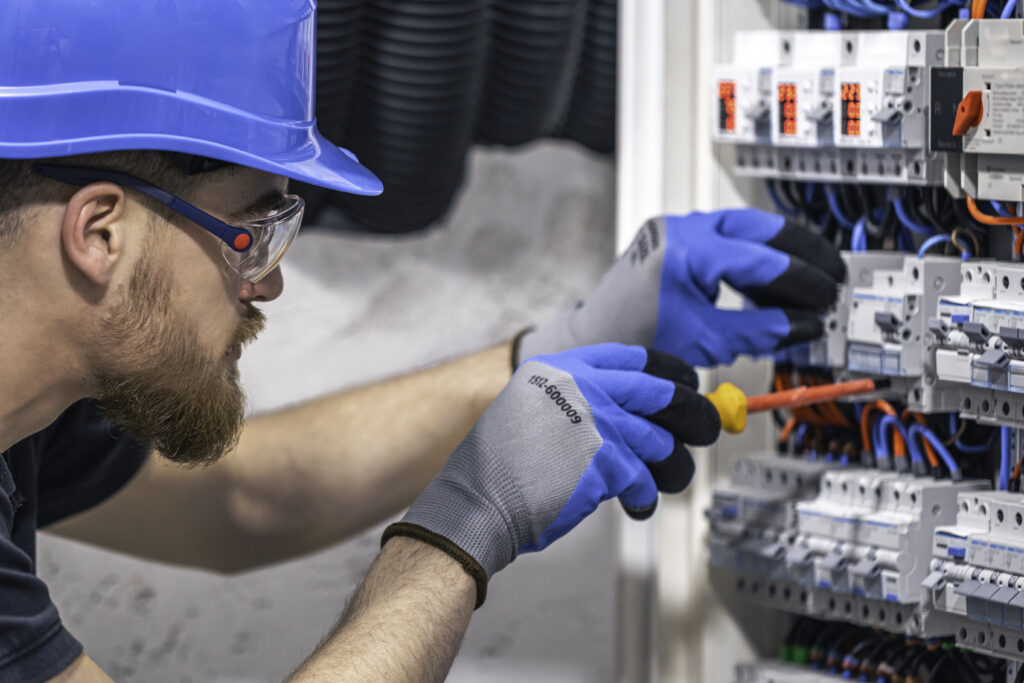 Male electrician working in a switchboard with fuses.